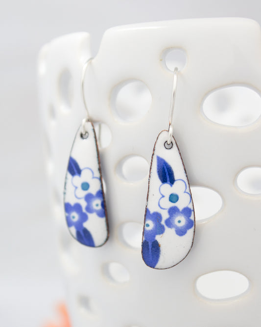 A pair of earrings with blue floral designs on a white background.