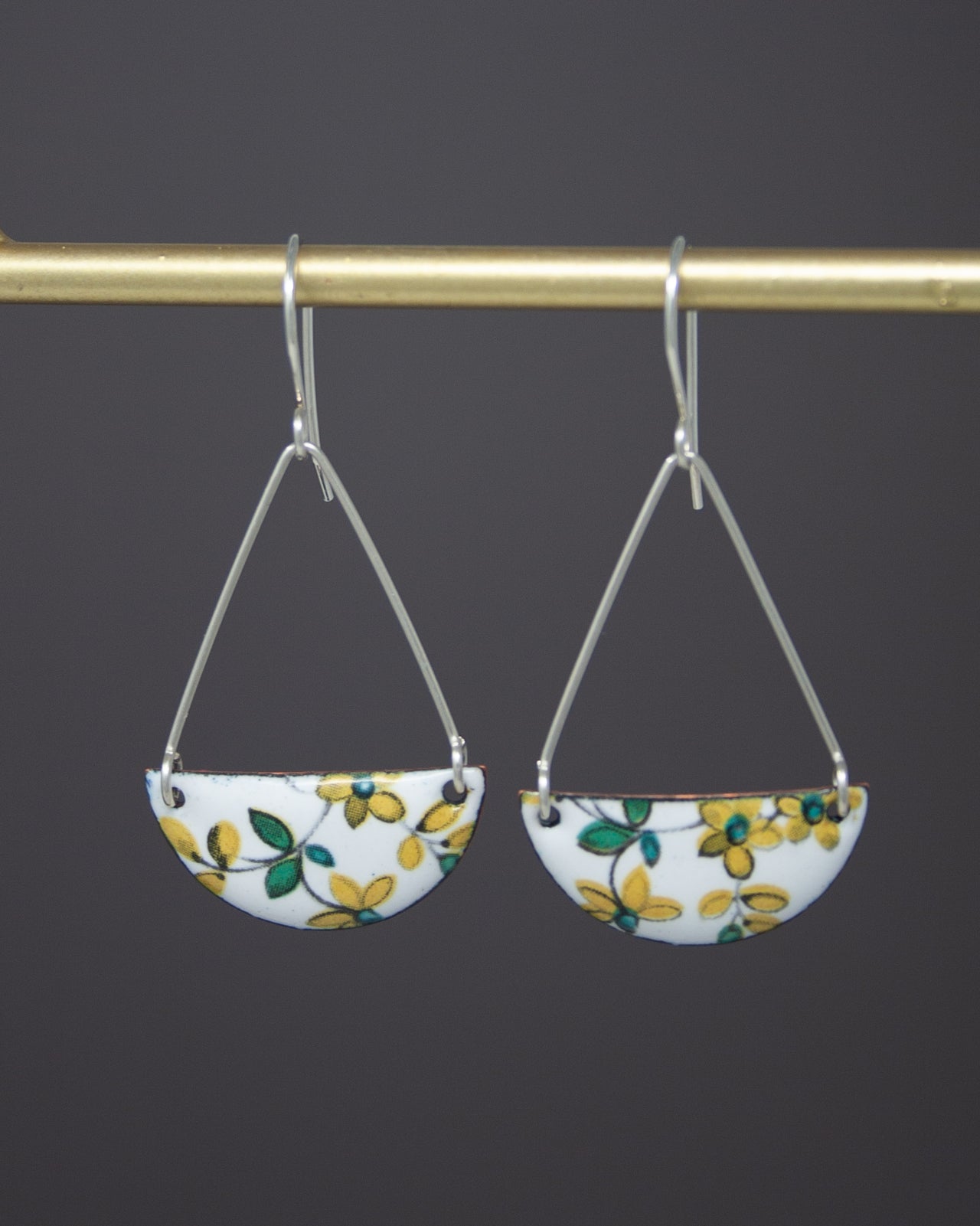 A pair of earrings with a floral pattern on a dark background.