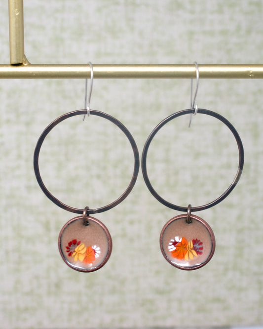 a pair of hoop earrings with a flower painted on them