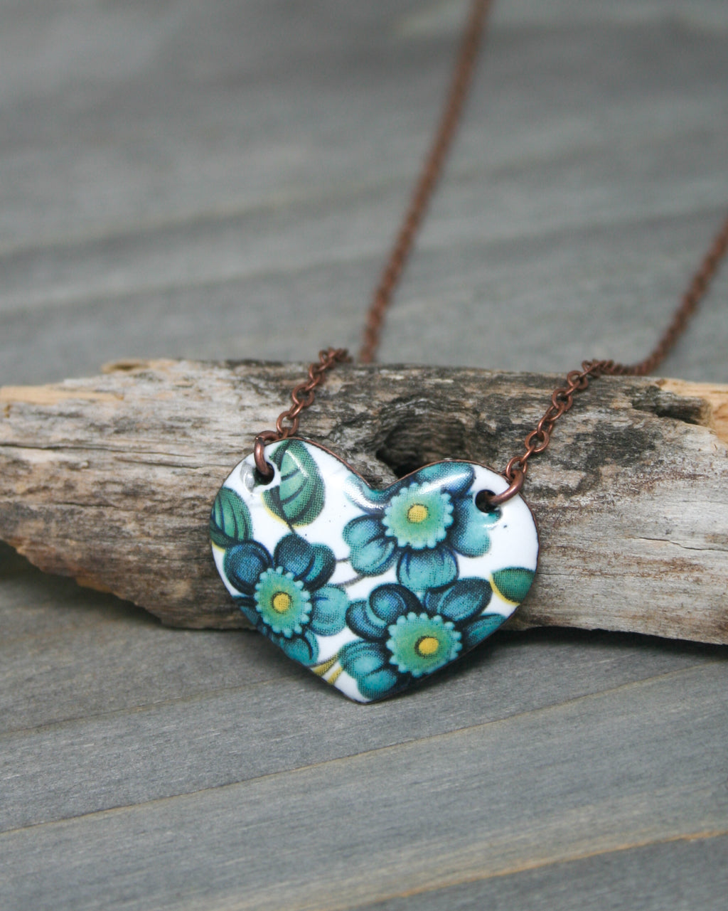 a heart shaped necklace with flowers painted on it