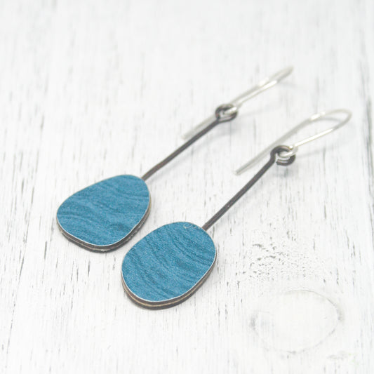 a pair of blue wooden earrings on a white table