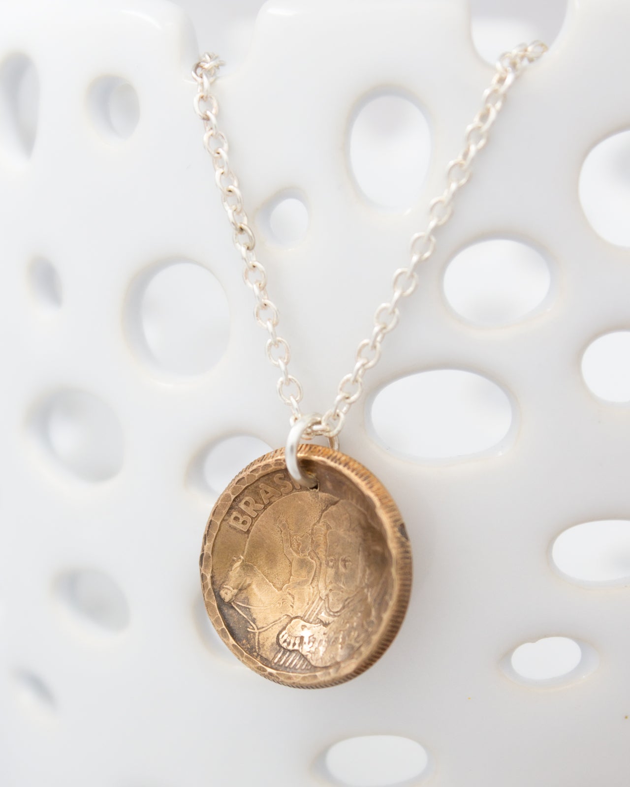 A necklace with a pendant made from a coin, featuring a portrait of a person.