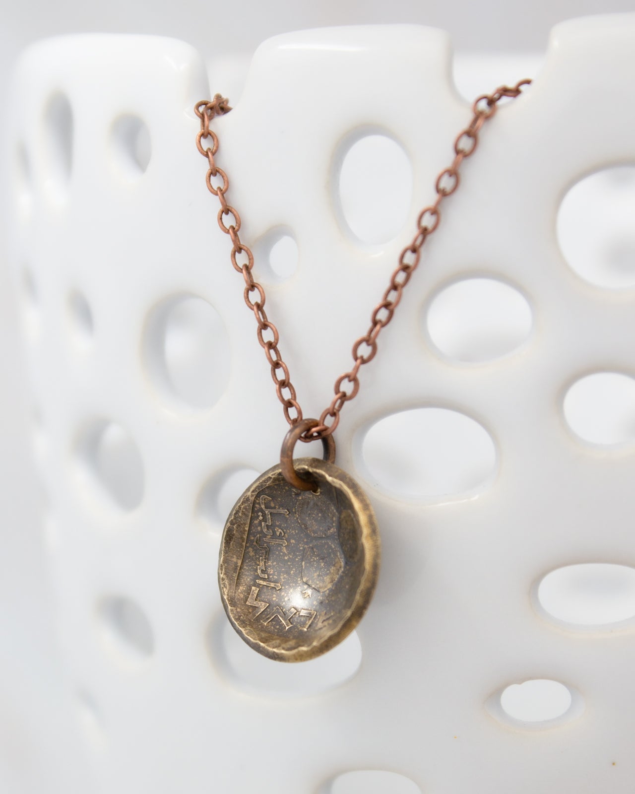 A necklace with a round metal pendant featuring an engraved design.
