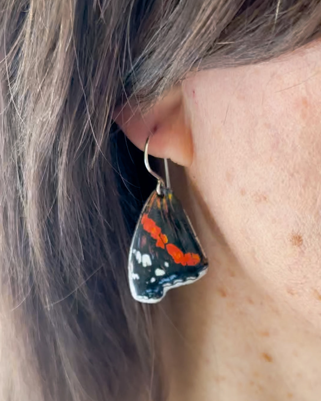 a close up of a person wearing a pair of earrings