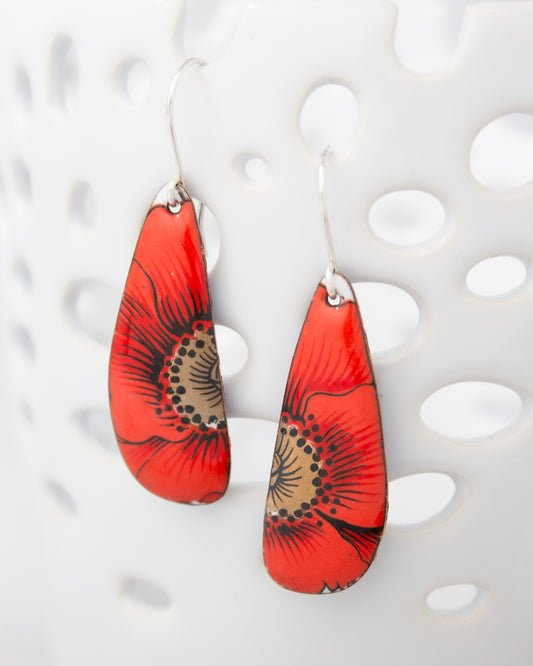 A pair of red earrings with a floral design on the pendants.
