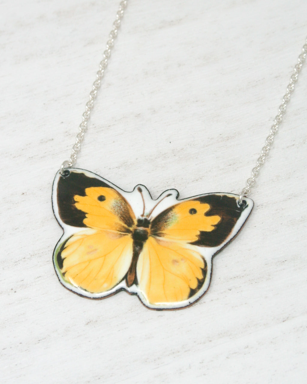 a yellow and black butterfly on a silver chain