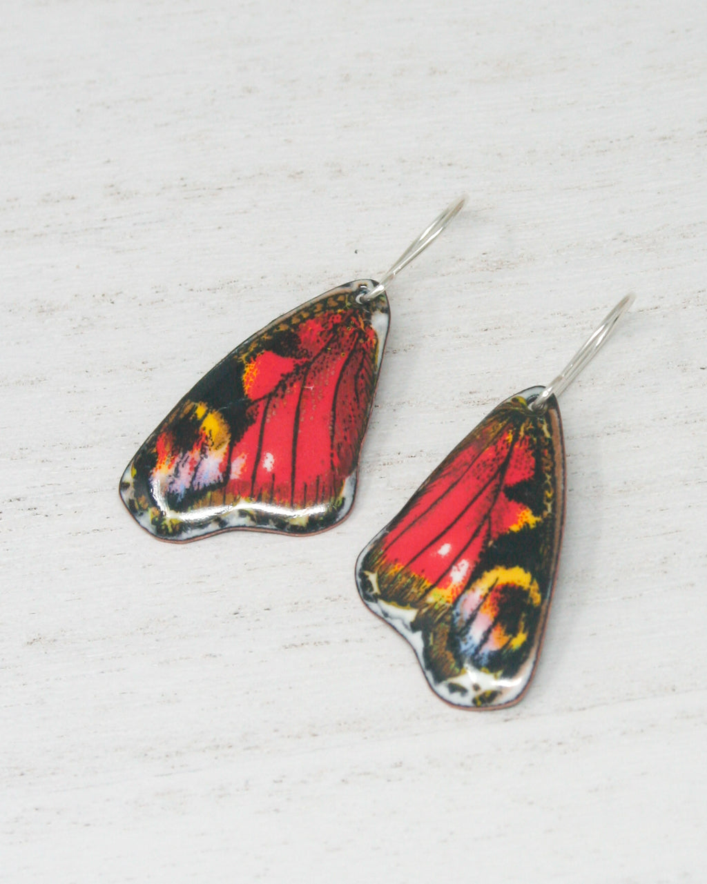 a pair of red and black butterfly shaped earrings