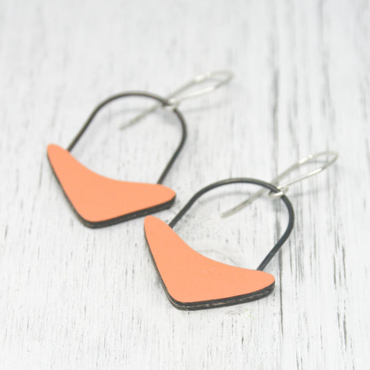 a pair of orange and black earrings sitting on top of a white table