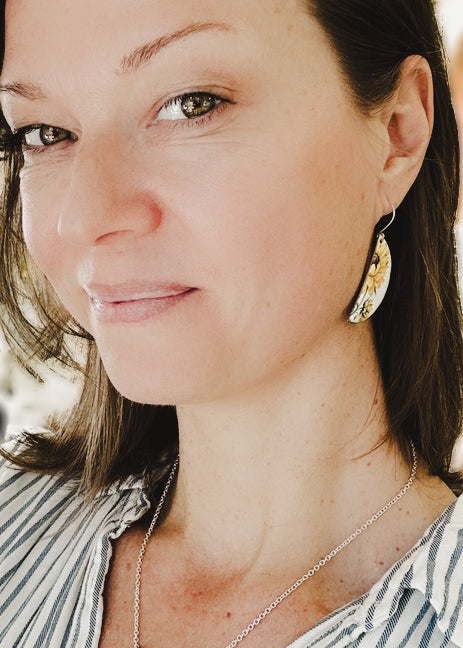 a woman wearing a striped shirt and a pair of earrings