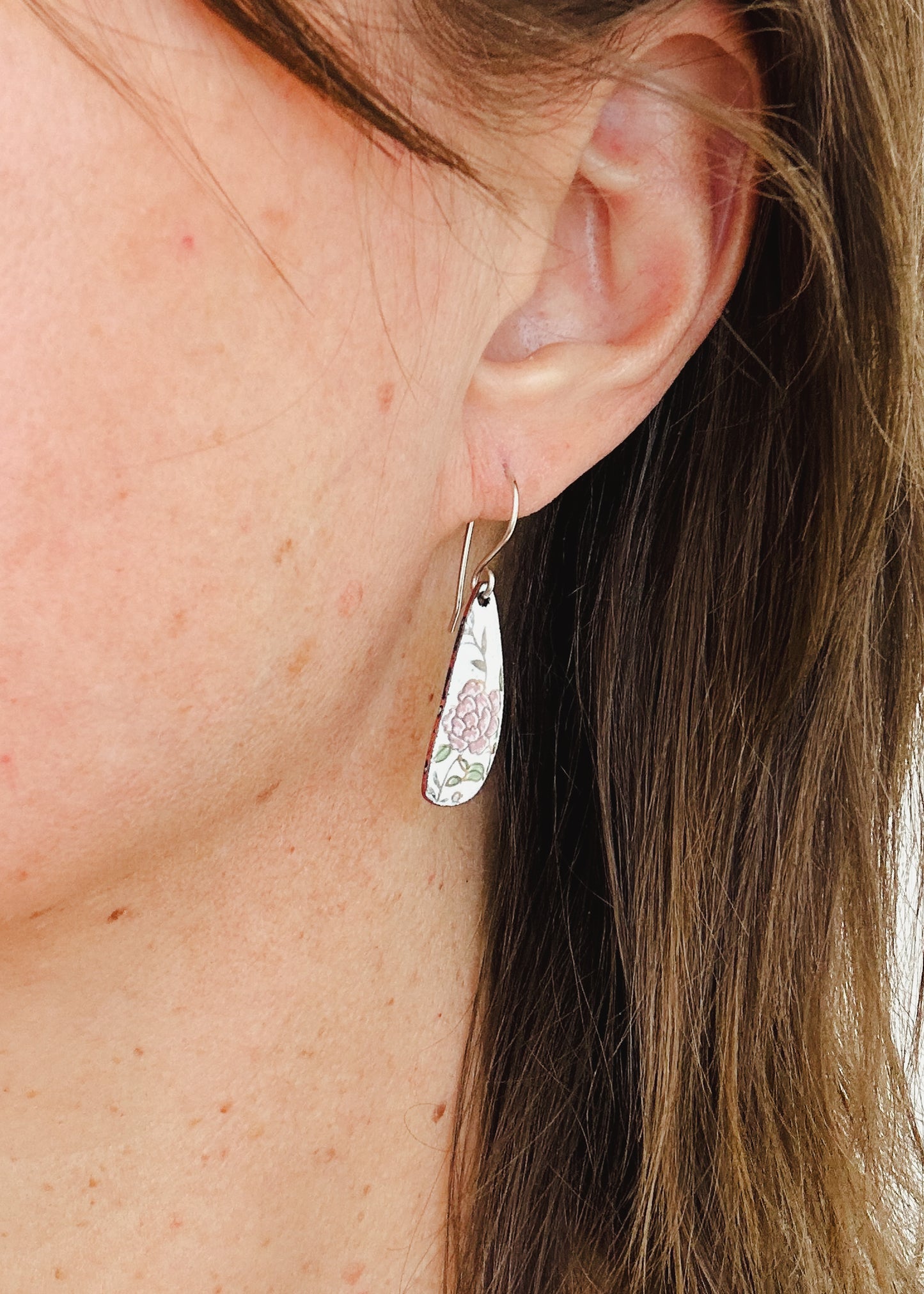 a close up of a person wearing a pair of earrings