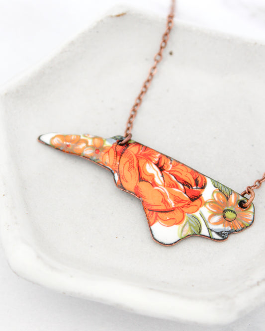A necklace with a floral design in orange and white colors.