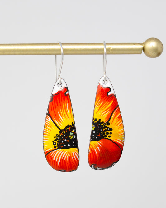 A pair of earrings with a vibrant floral design, featuring red and yellow petals with black centers.