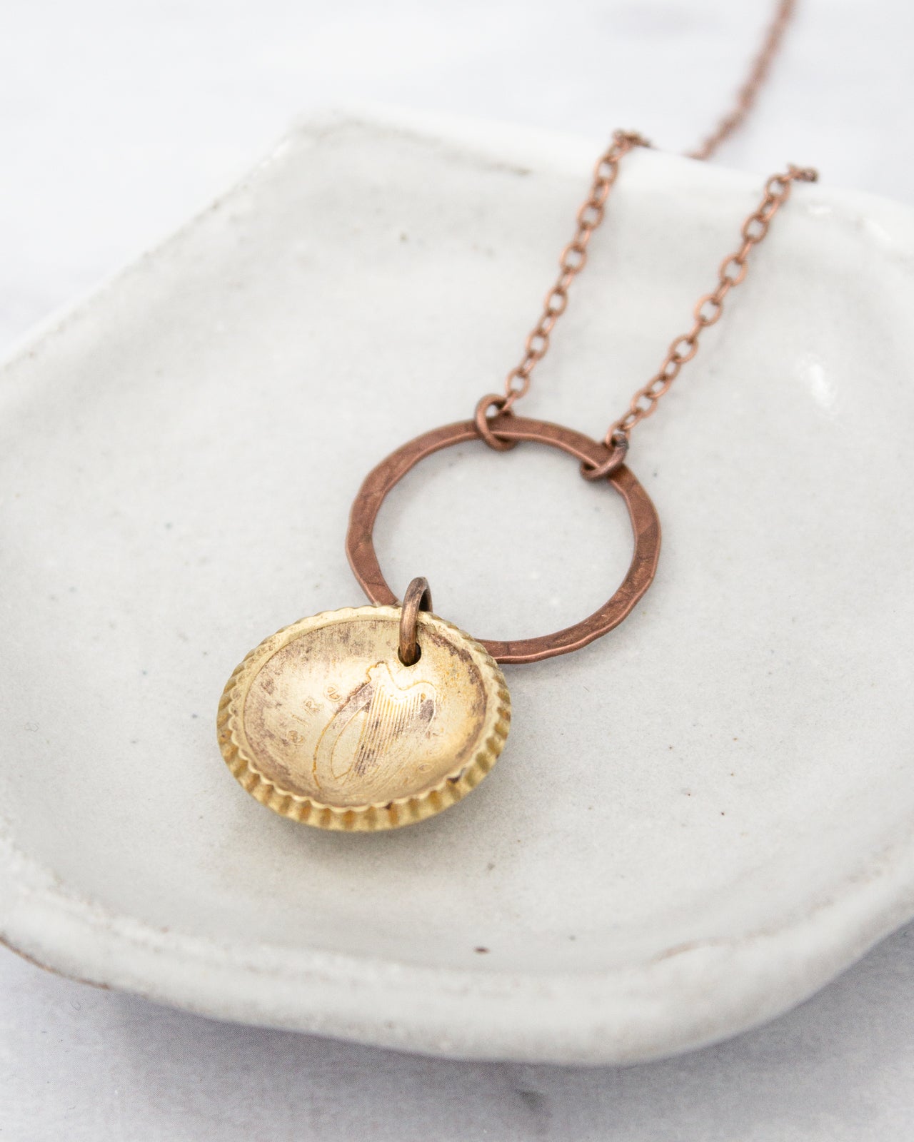 A necklace with a round pendant featuring a harp design, hanging from a chain.