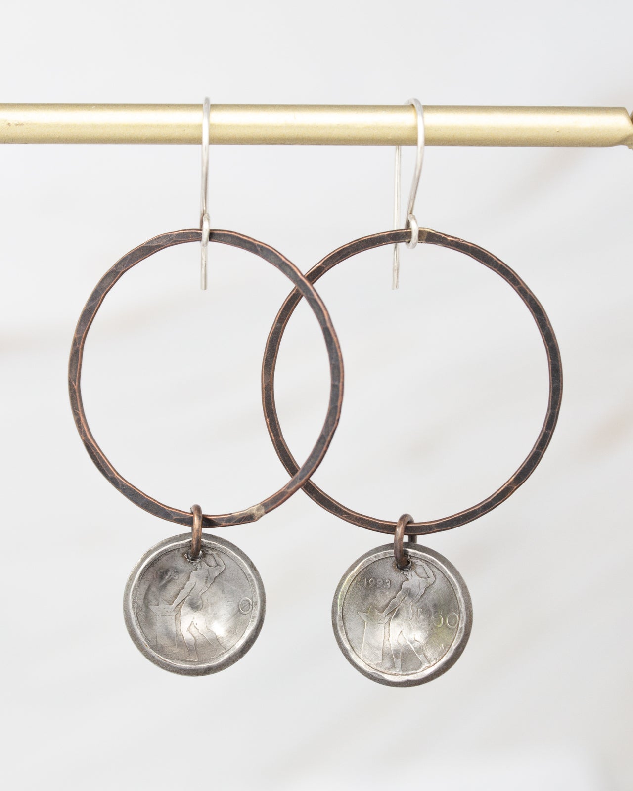 A pair of large hoop earrings with metal charms hanging from them.