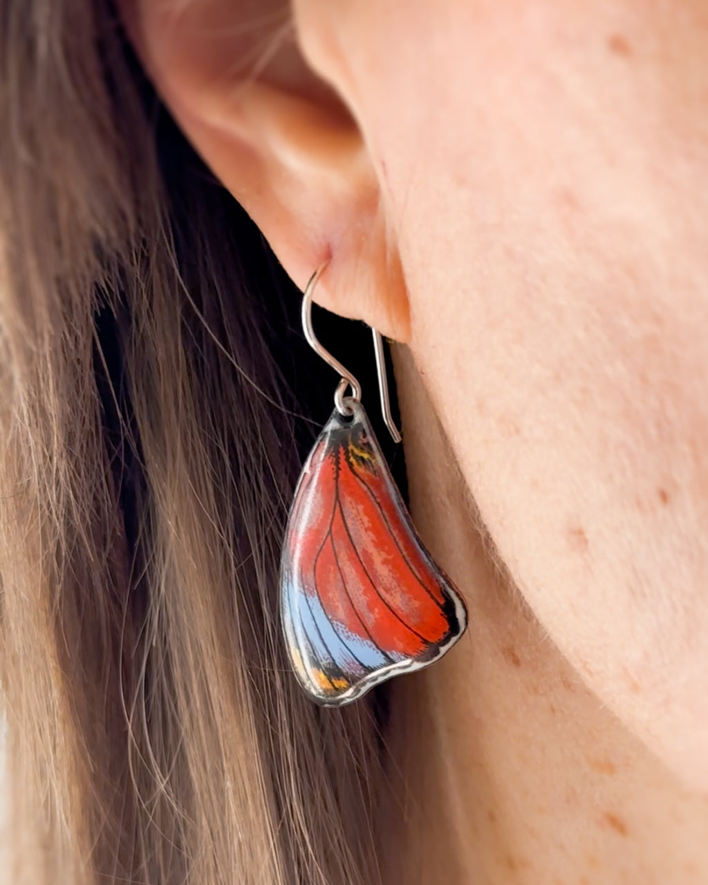 a close up of a person wearing a pair of earrings