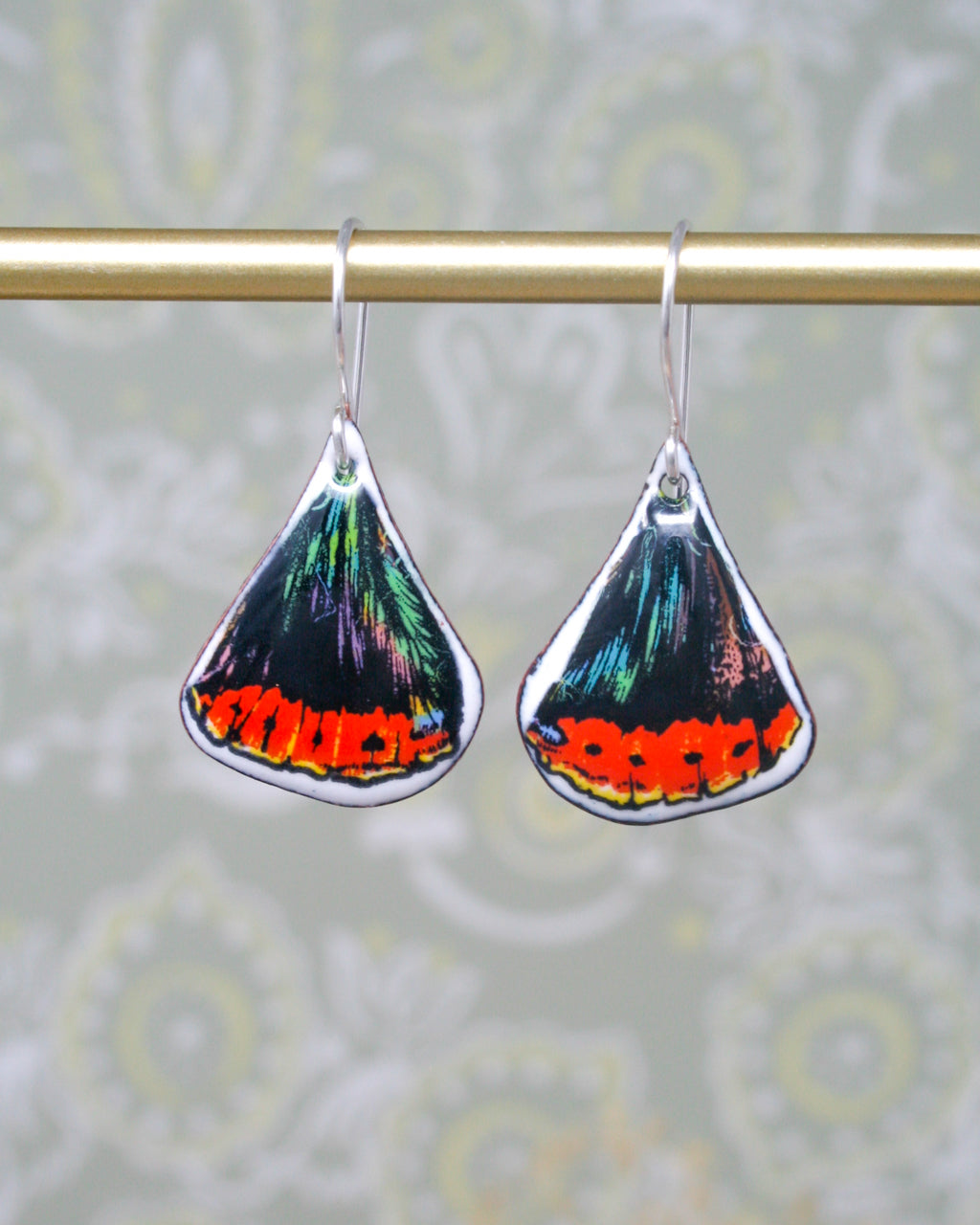 a pair of colorful earrings hanging from a metal rod