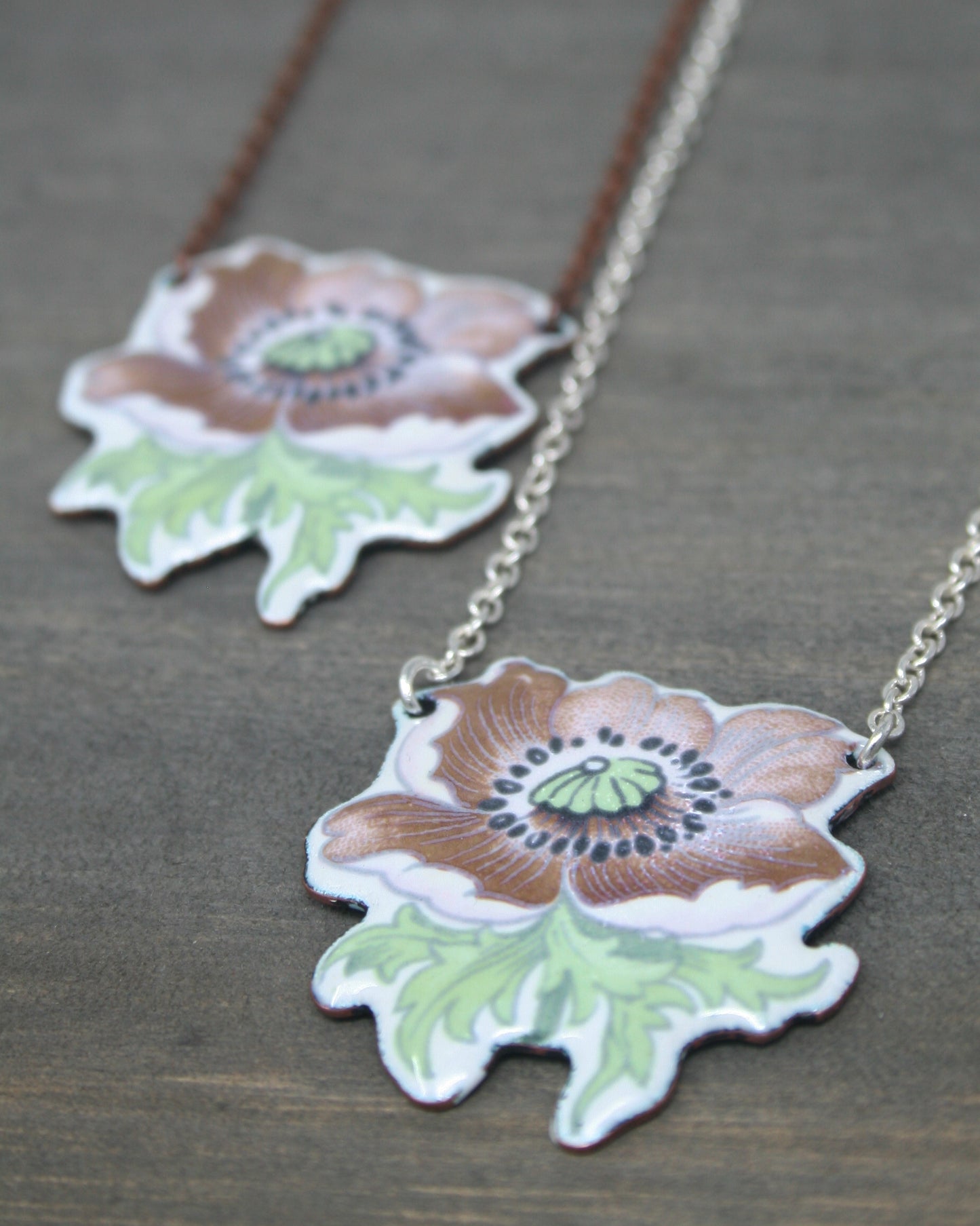 two necklaces with flowers on them sitting on a table