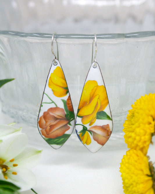 a pair of earrings with flowers painted on them