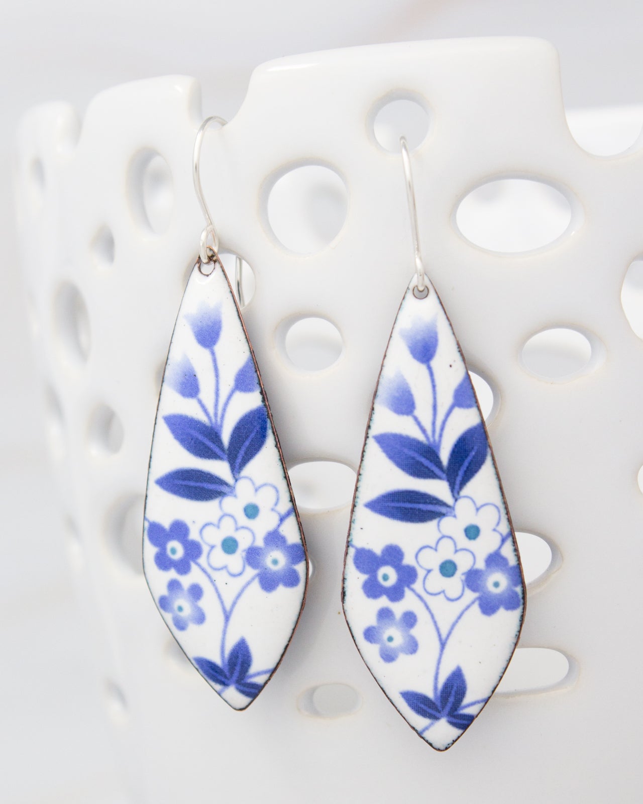 A pair of earrings with blue and white floral designs on a white background.