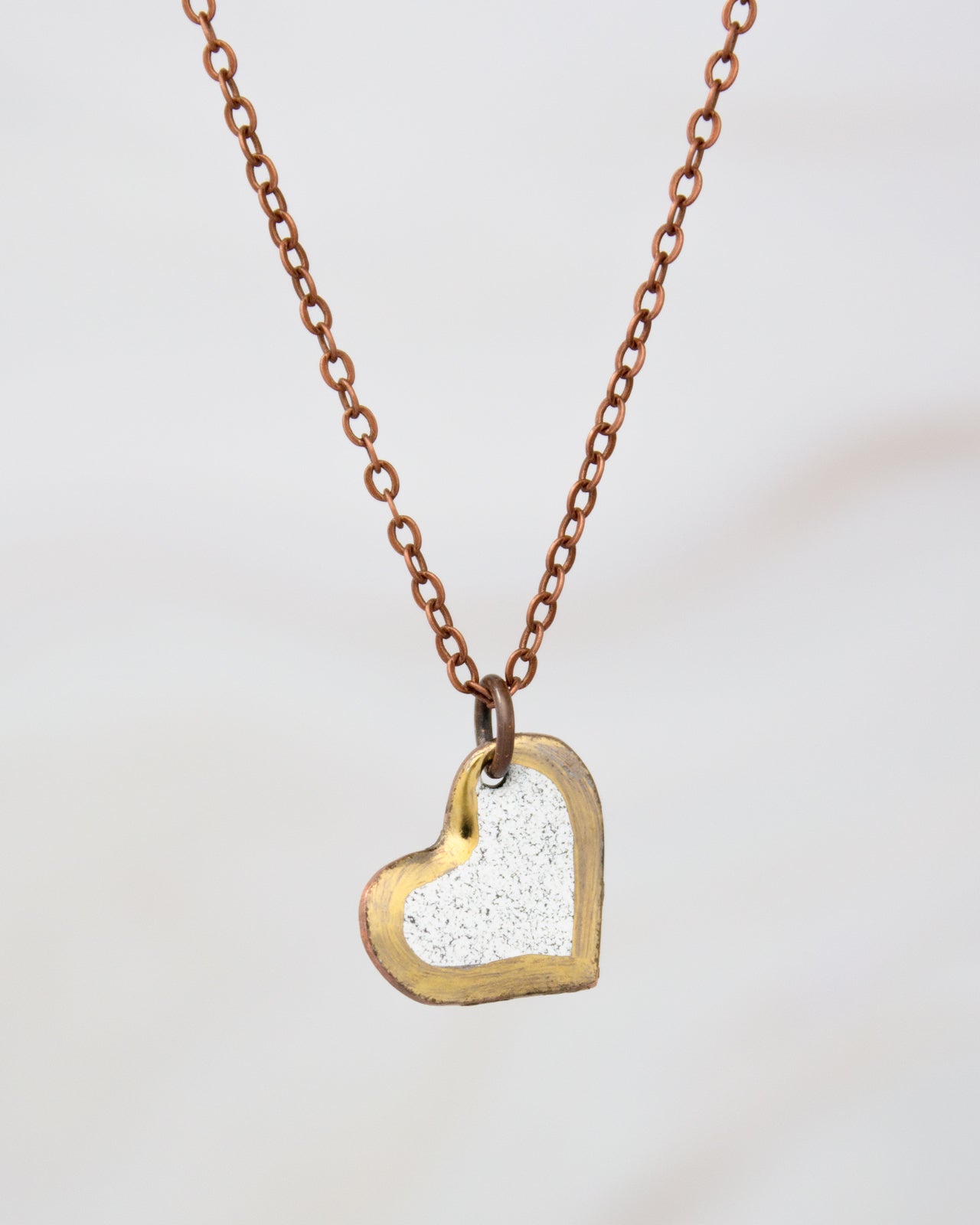 A delicate heart-shaped pendant necklace with a copper-colored chain.