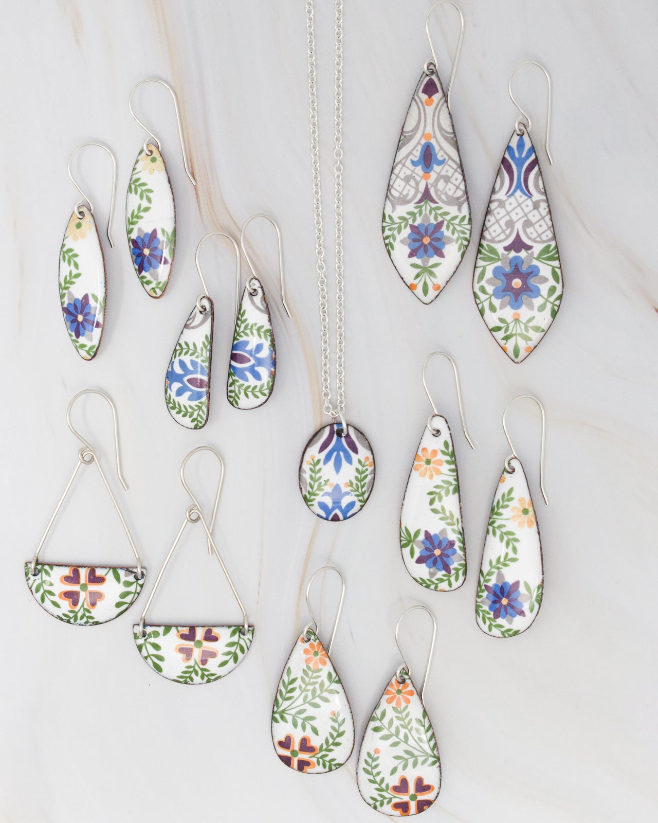 a collection of earrings and a necklace featuring colorful floral designs.