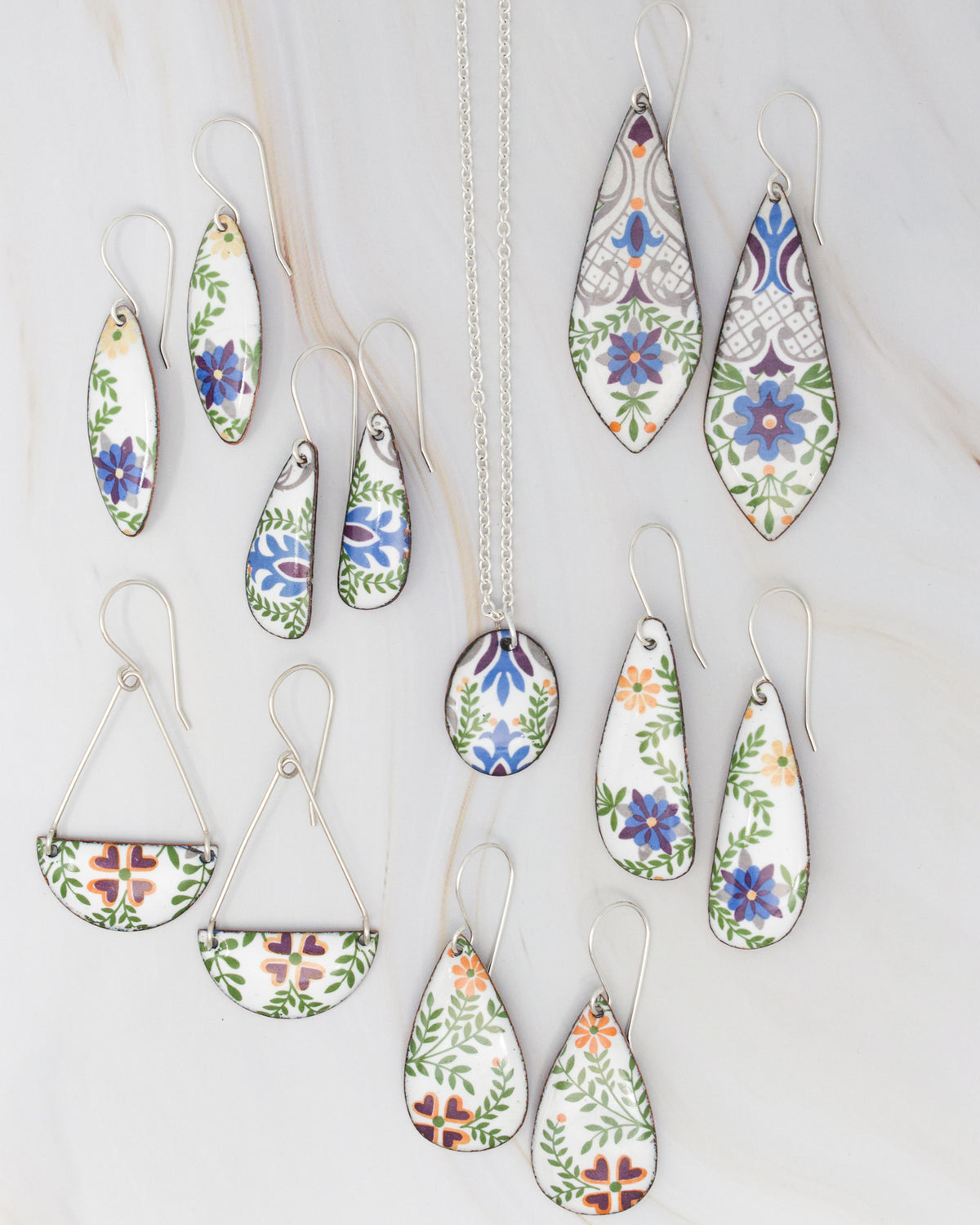 a collection of earrings and a necklace featuring colorful floral designs.