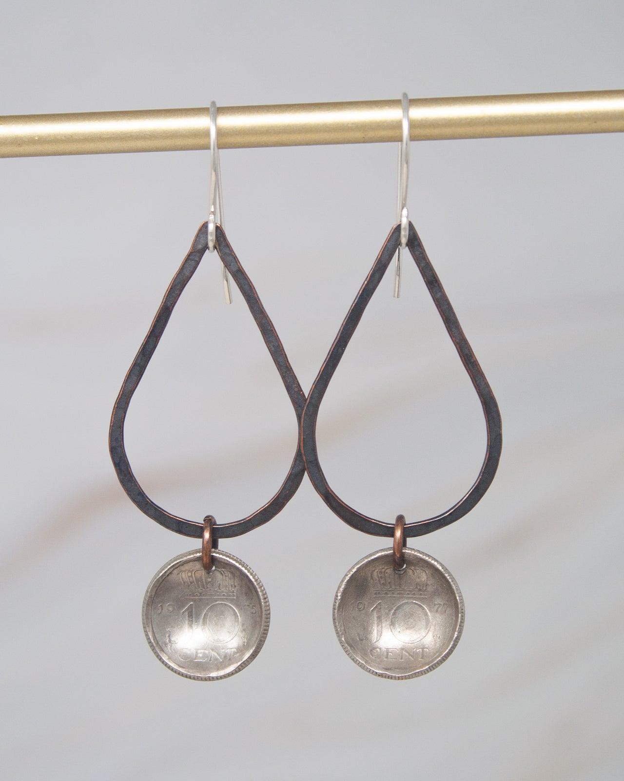 A pair of earrings with a metal frame and dangling circular pendants, each featuring a 10 cent coin design.