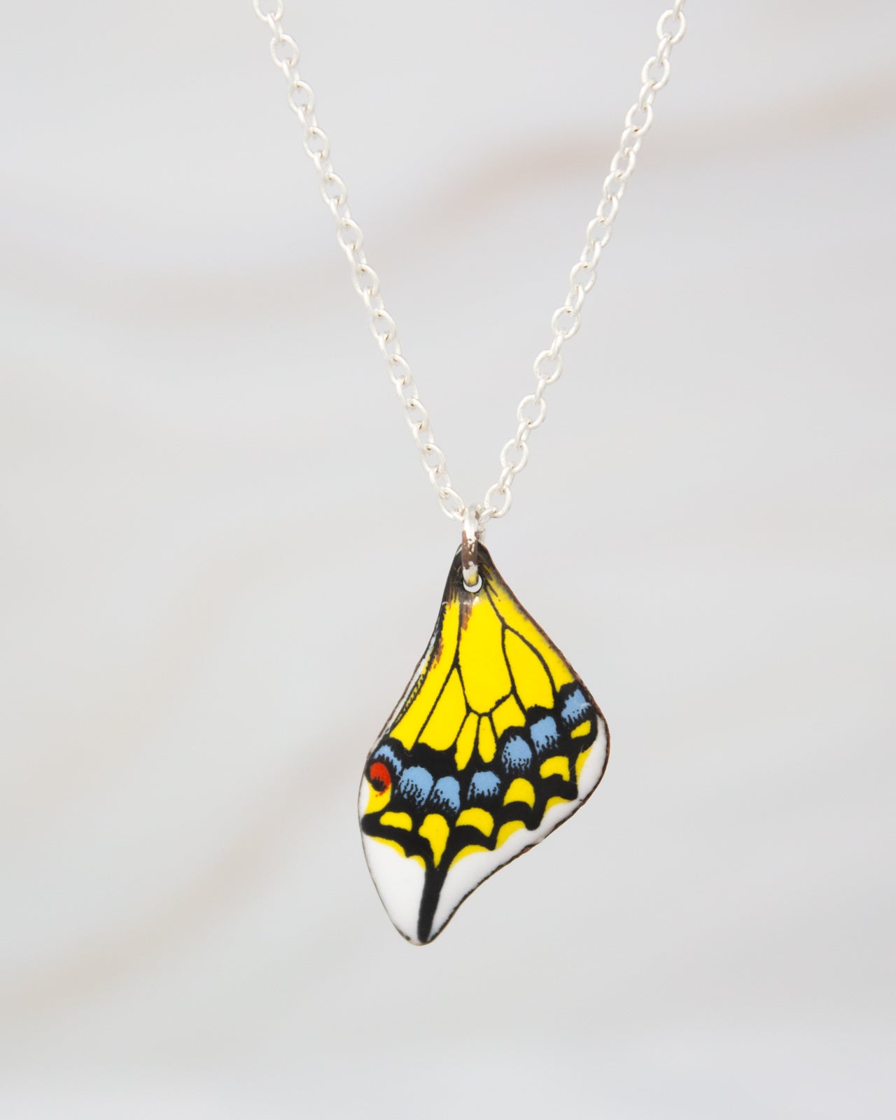 A colorful butterfly-shaped pendant necklace with a yellow and black design.