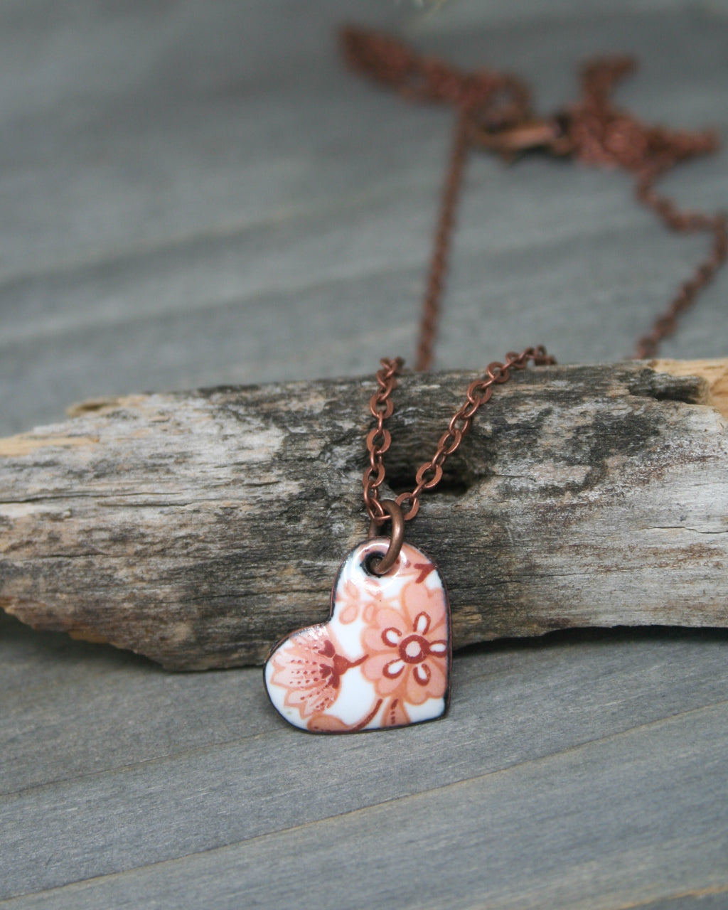 a heart shaped pendant on a wooden piece of wood