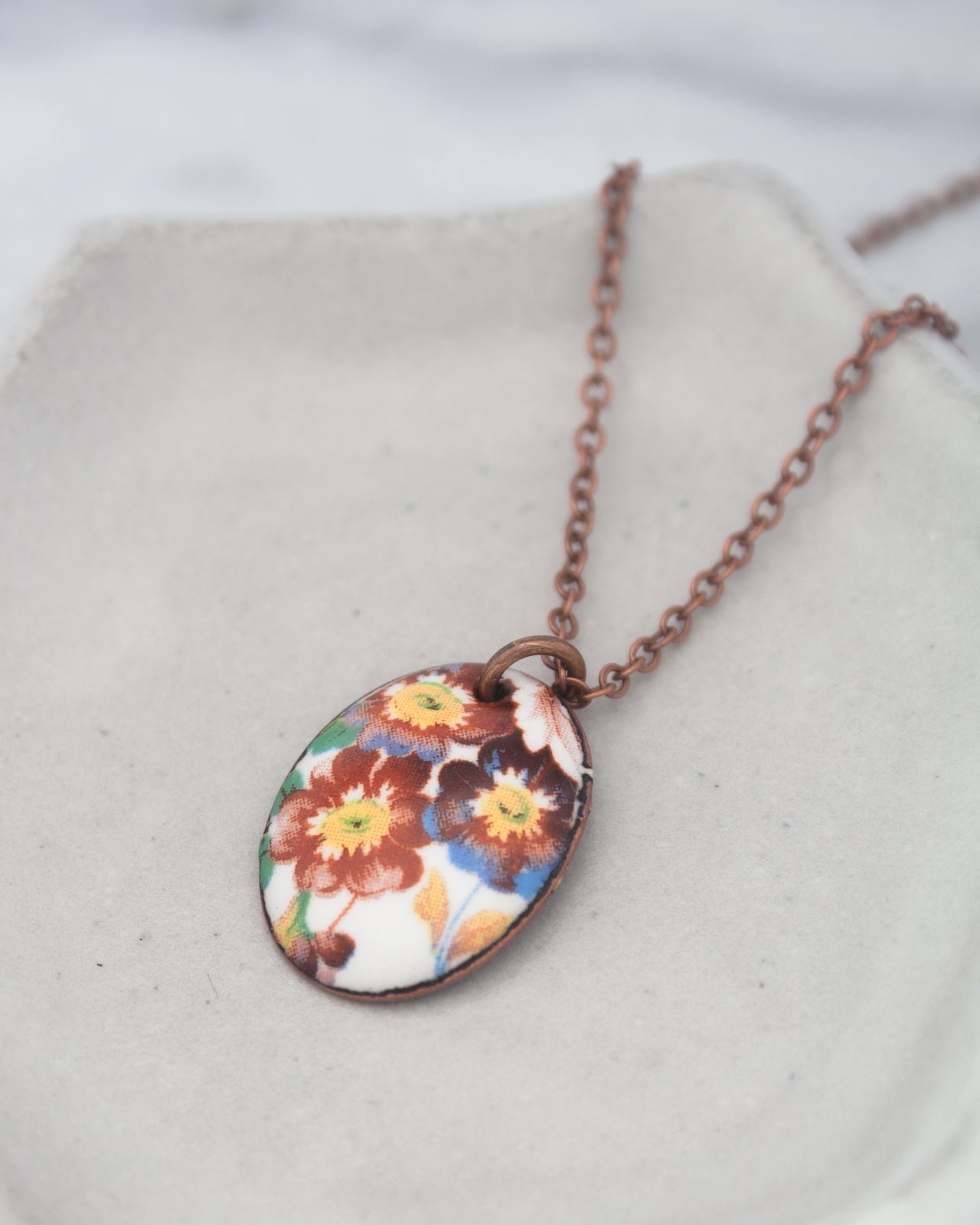 A necklace with a pendant featuring a floral design in various colors.