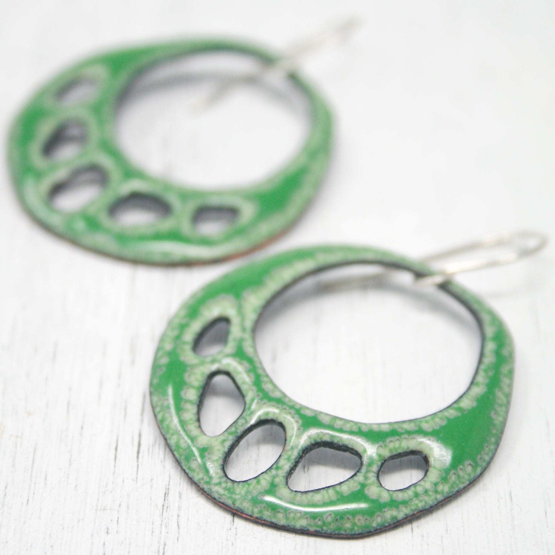 a pair of green earrings on a white surface