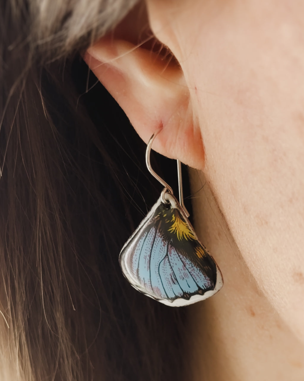 a close up of a person wearing a pair of earrings