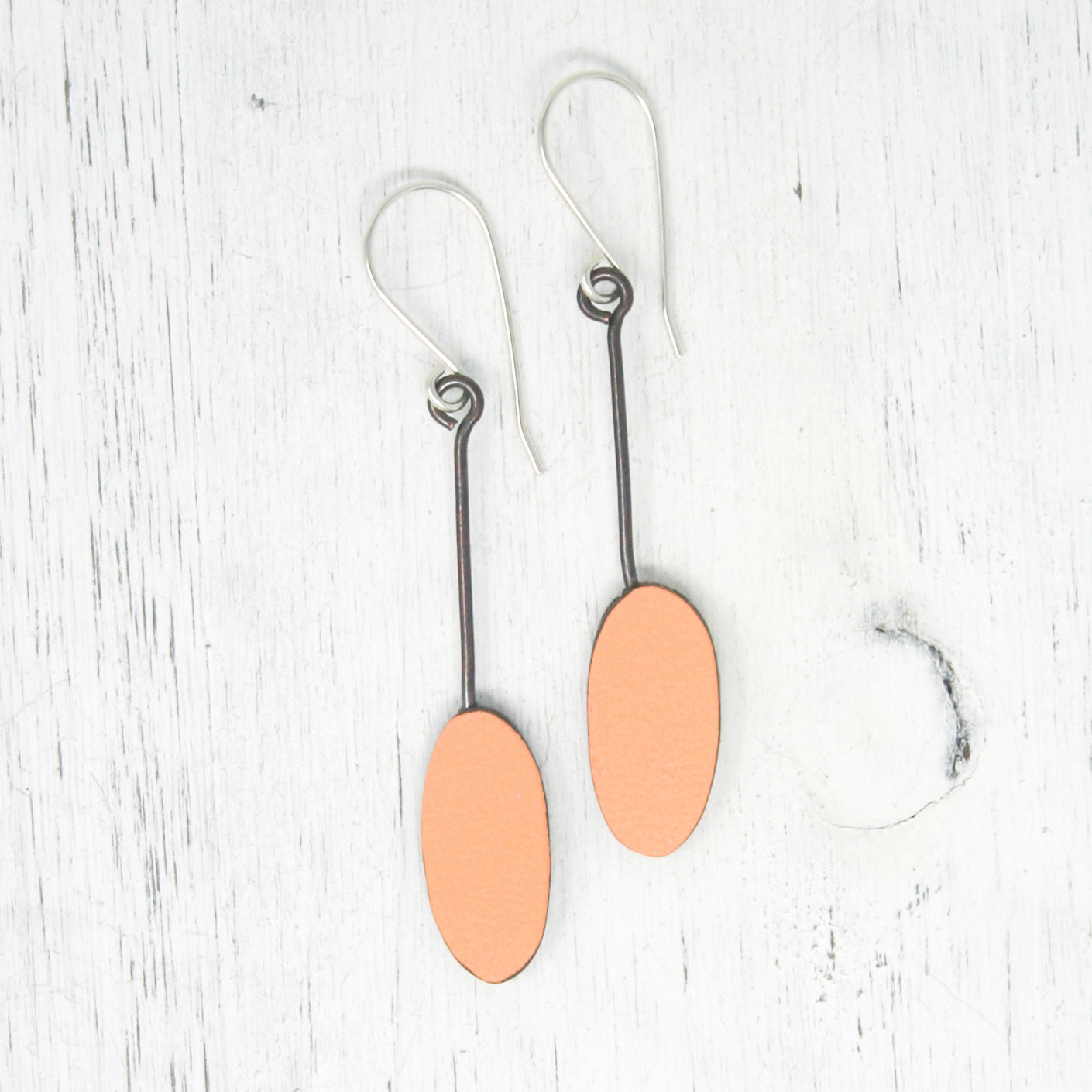 a pair of earrings with a wooden disc hanging from them