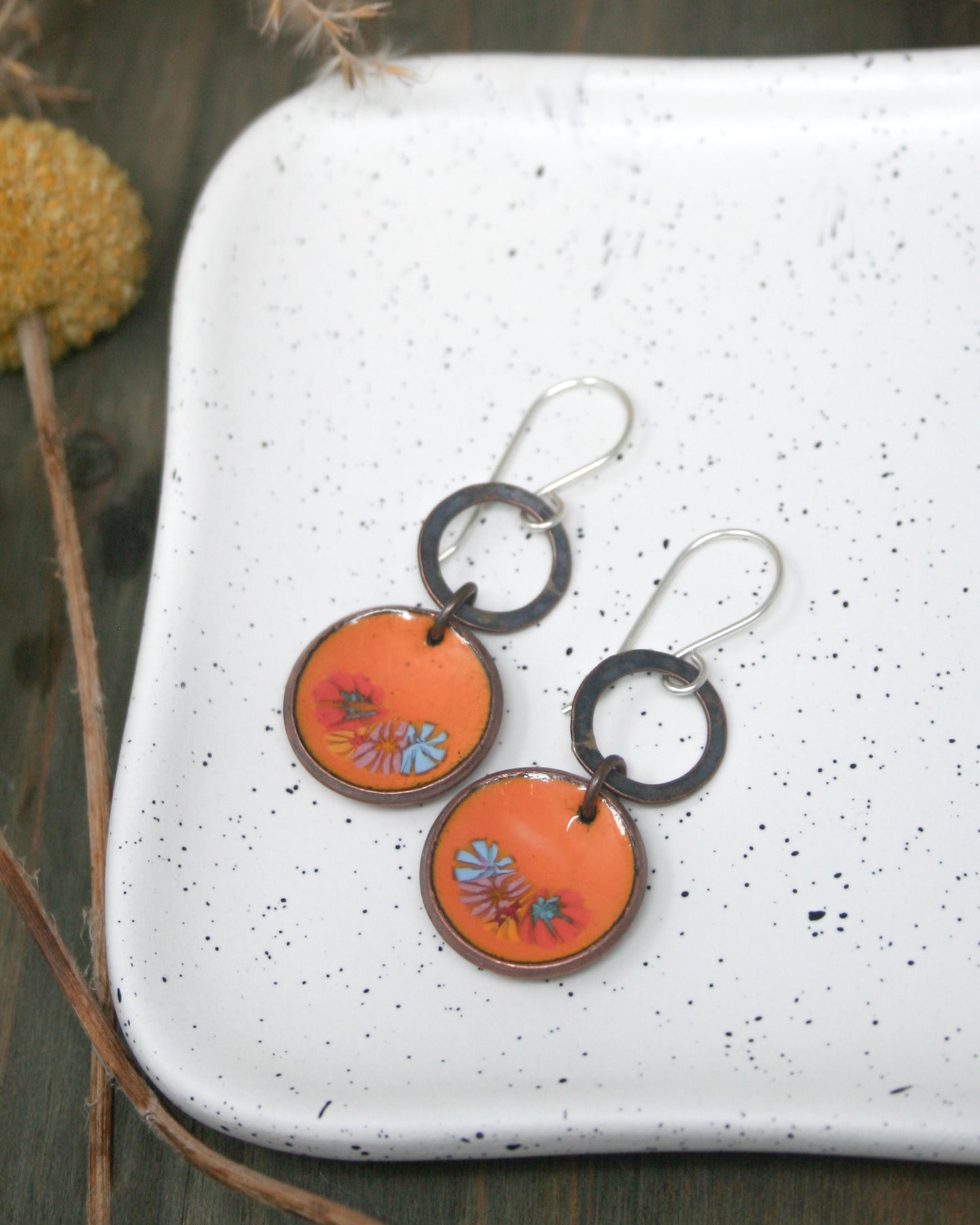 a pair of orange and black earrings sitting on top of a white plate