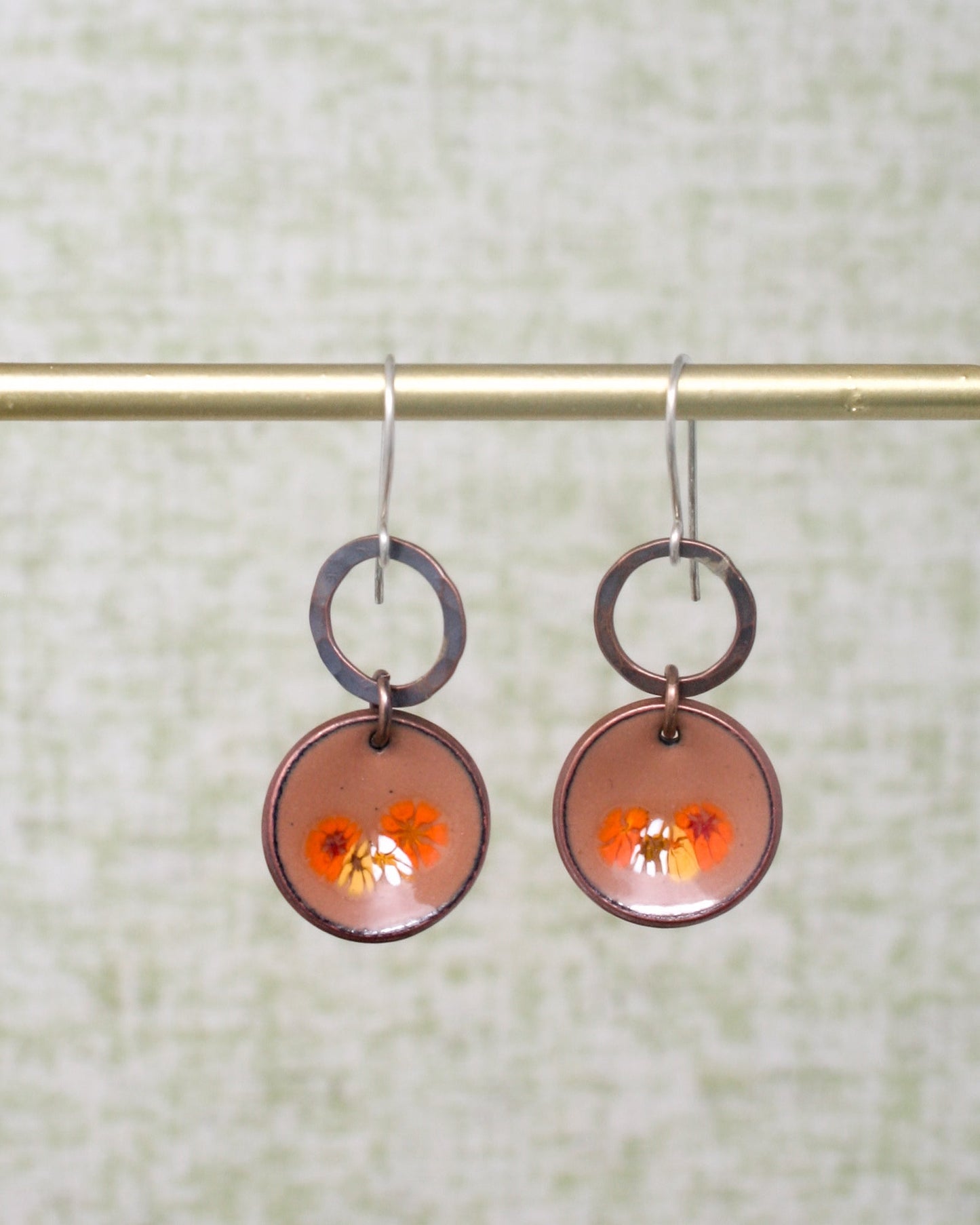 a pair of earrings hanging from a metal rod