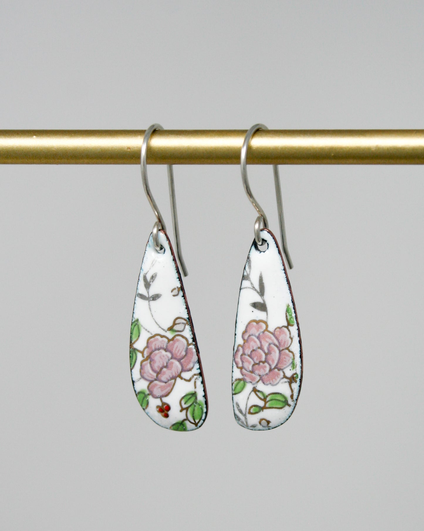 a pair of earrings hanging from a gold bar