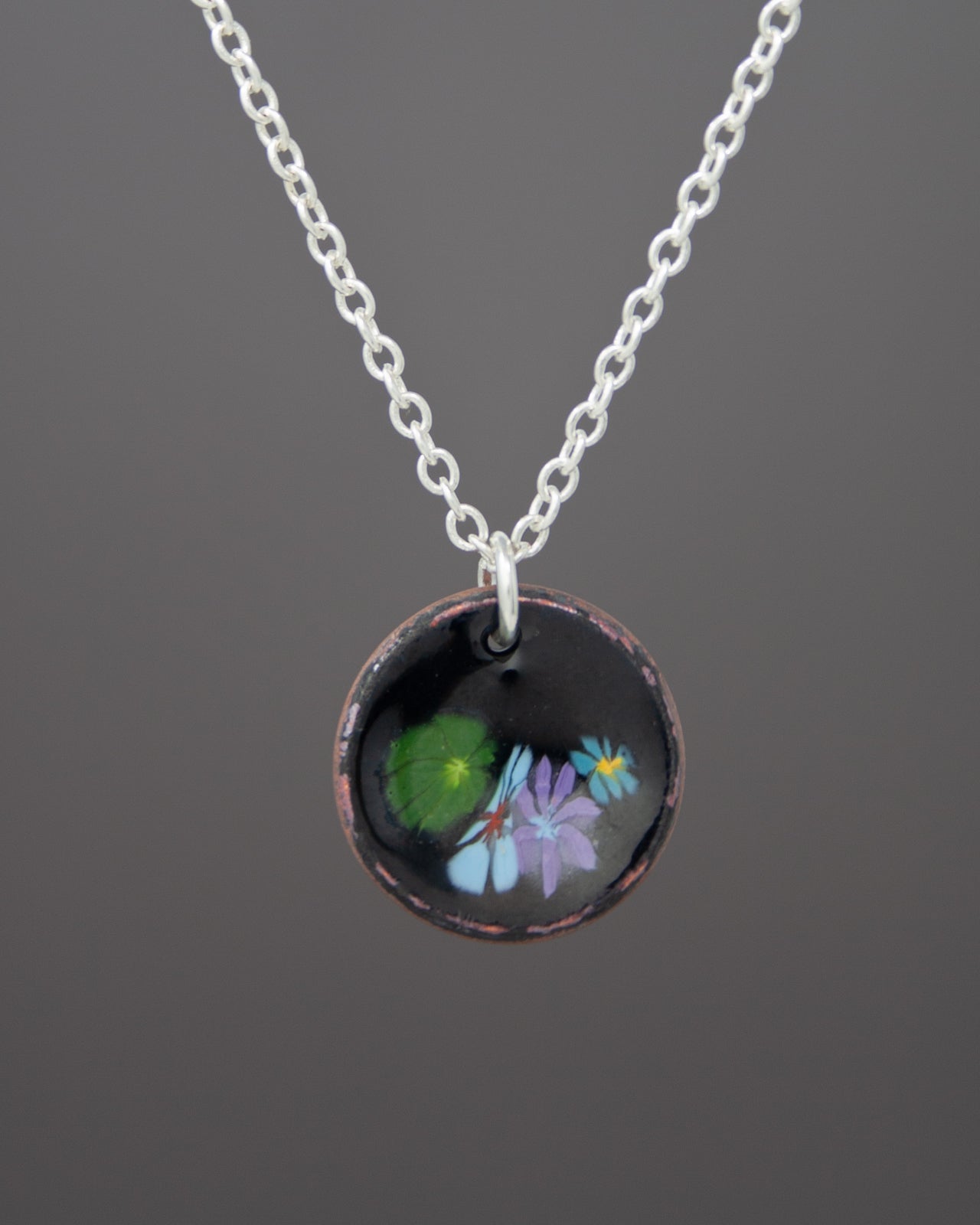 A necklace with a circular pendant featuring a floral design.