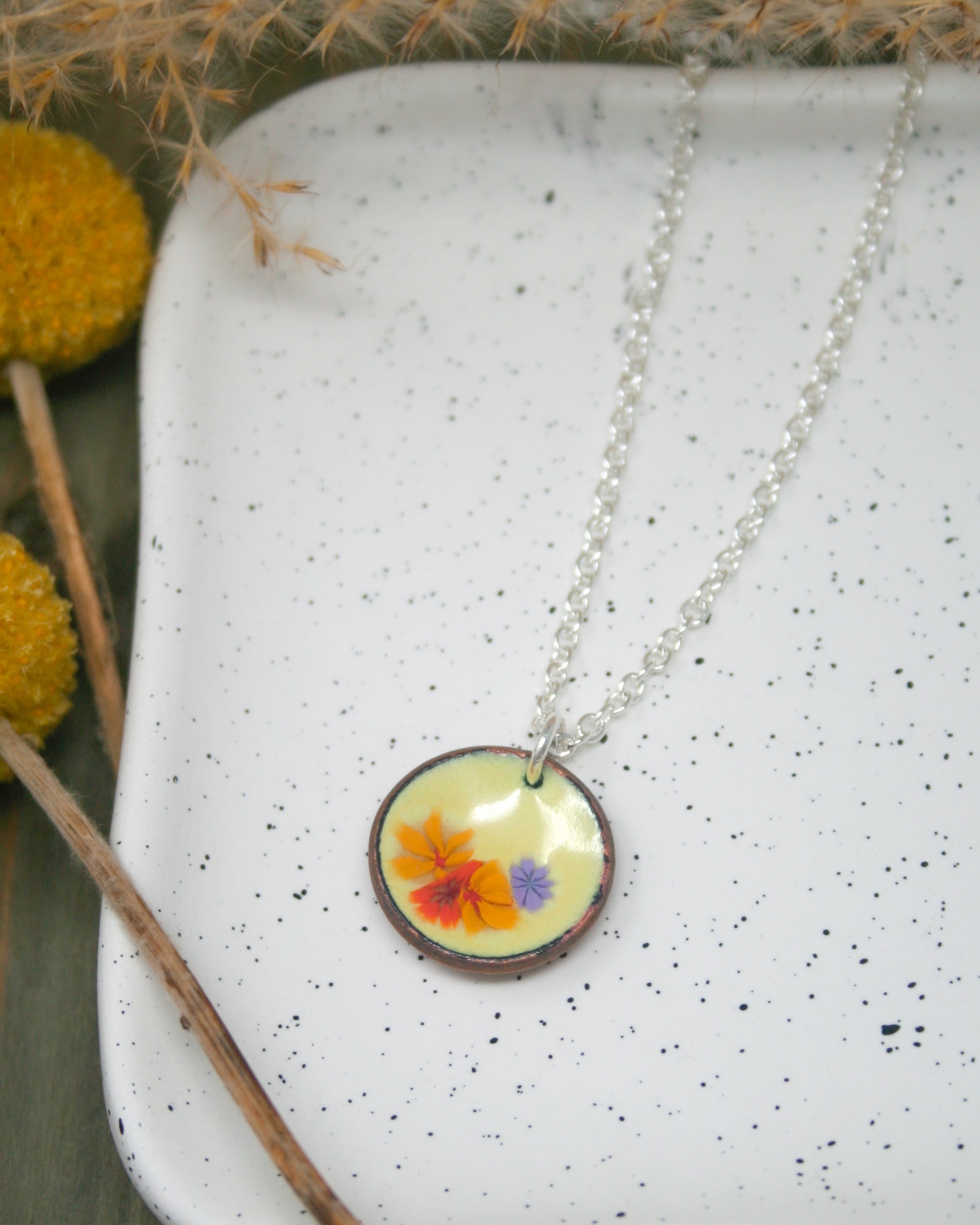 a necklace with a flower on it sitting on a plate