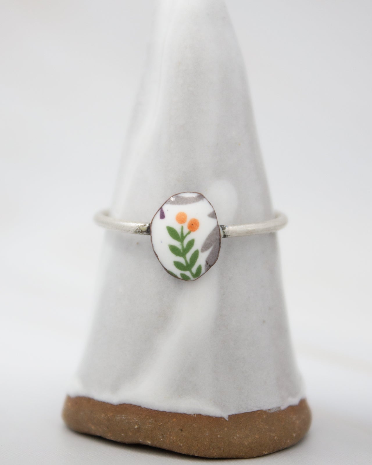 A white ceramic ring stand with a floral design on it.