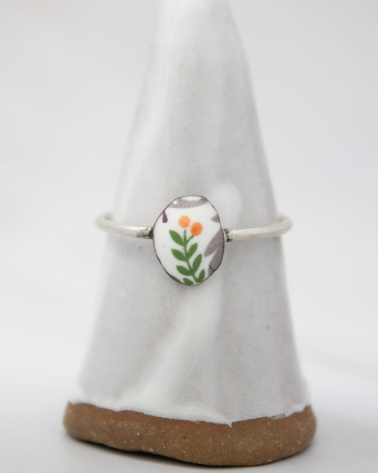 A white ceramic ring stand with a floral design on it.