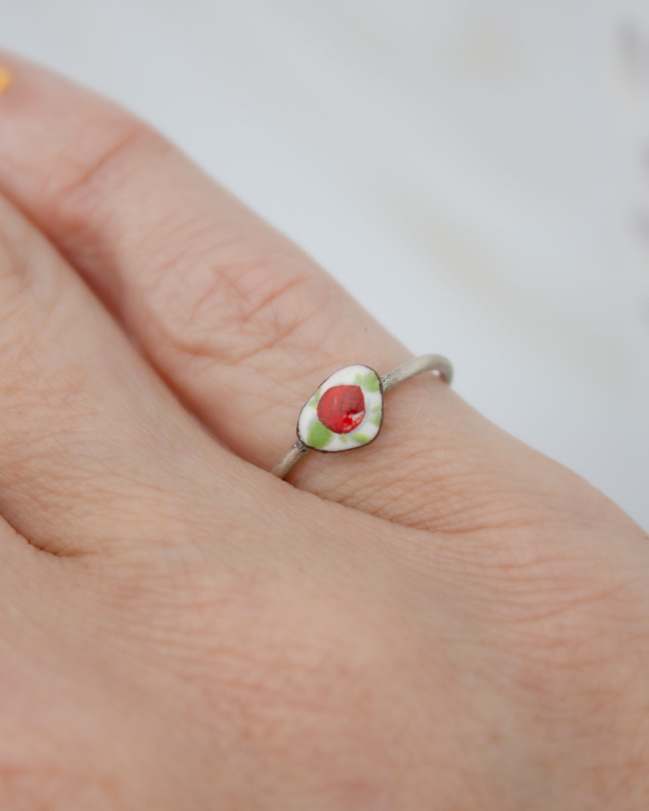 A close-up of a person's hand wearing a ring with a red and green design.