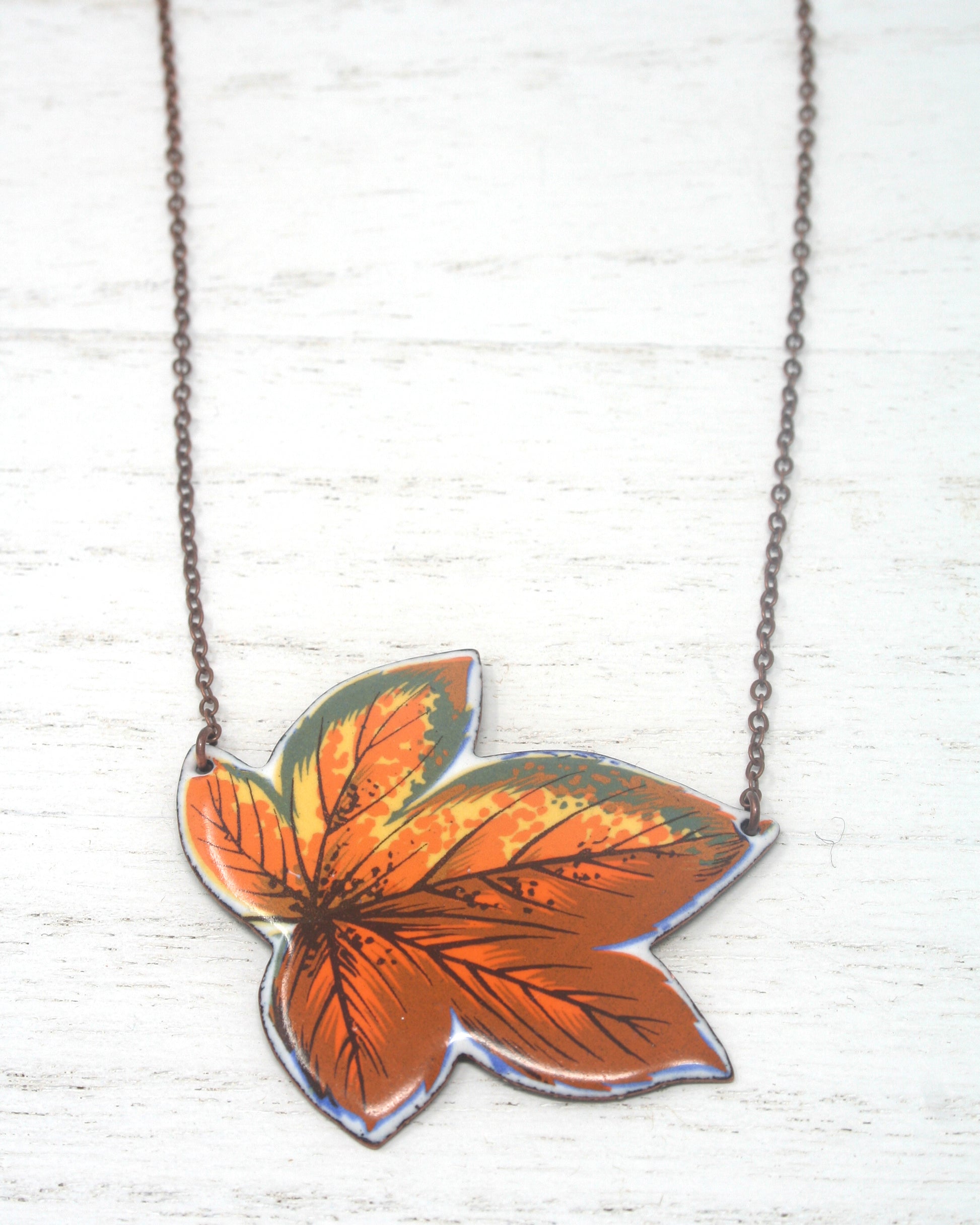 a necklace with an orange leaf on it