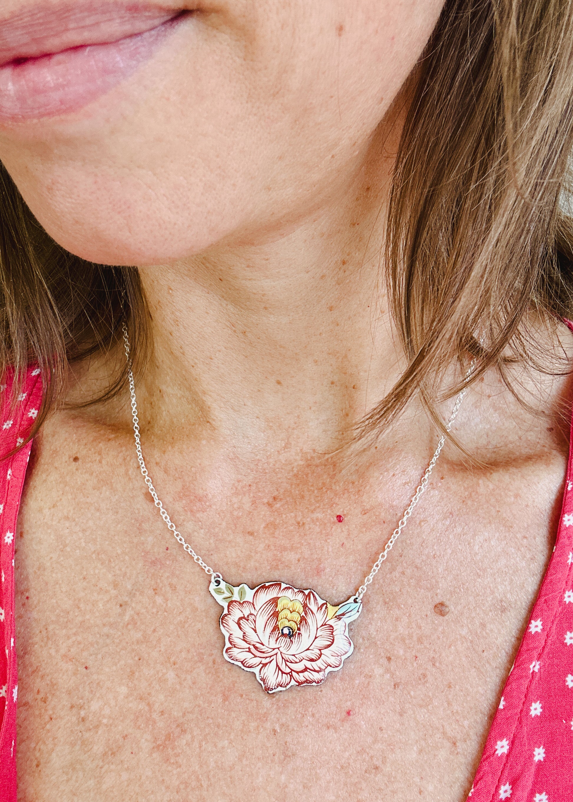 a woman wearing a necklace with a flower on it