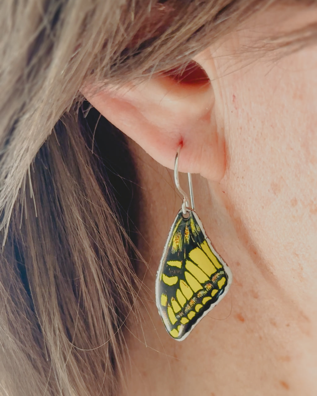 a close up of a person wearing a pair of earrings