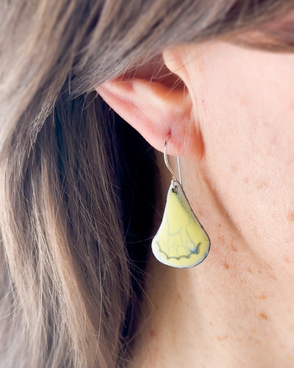 a close up of a person wearing a pair of earrings