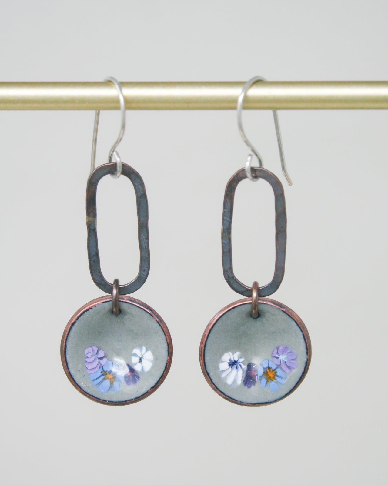 a pair of earrings with flowers painted on them