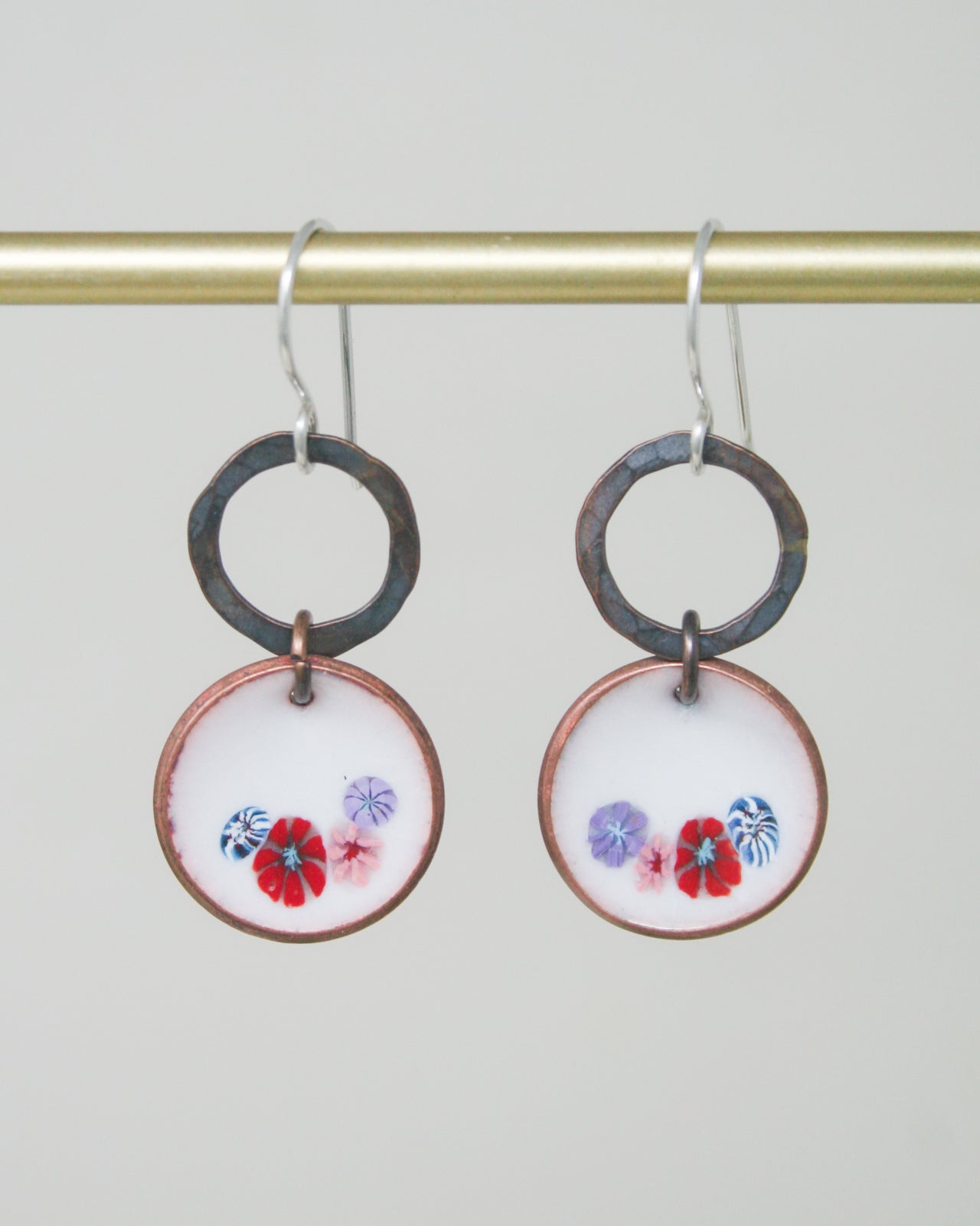 a pair of earrings with flowers painted on them