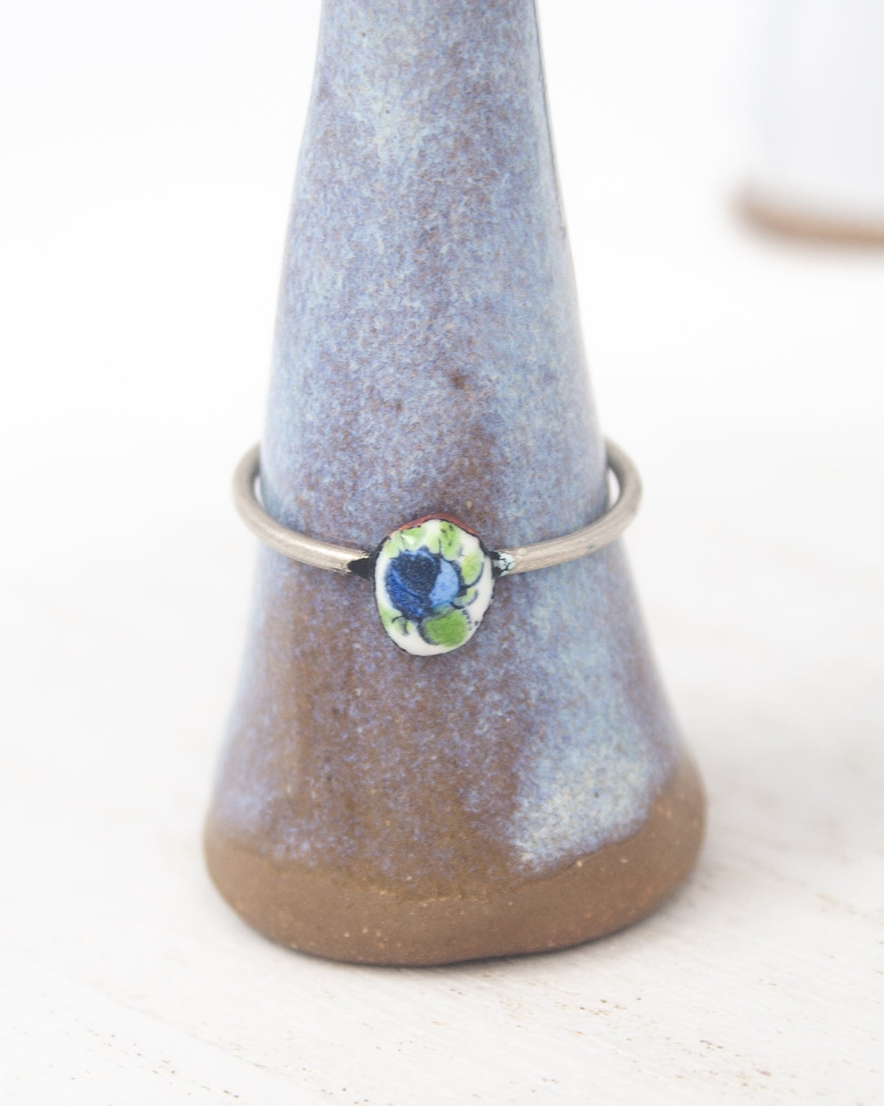 A ring with a blue and green floral design on a ceramic stand.