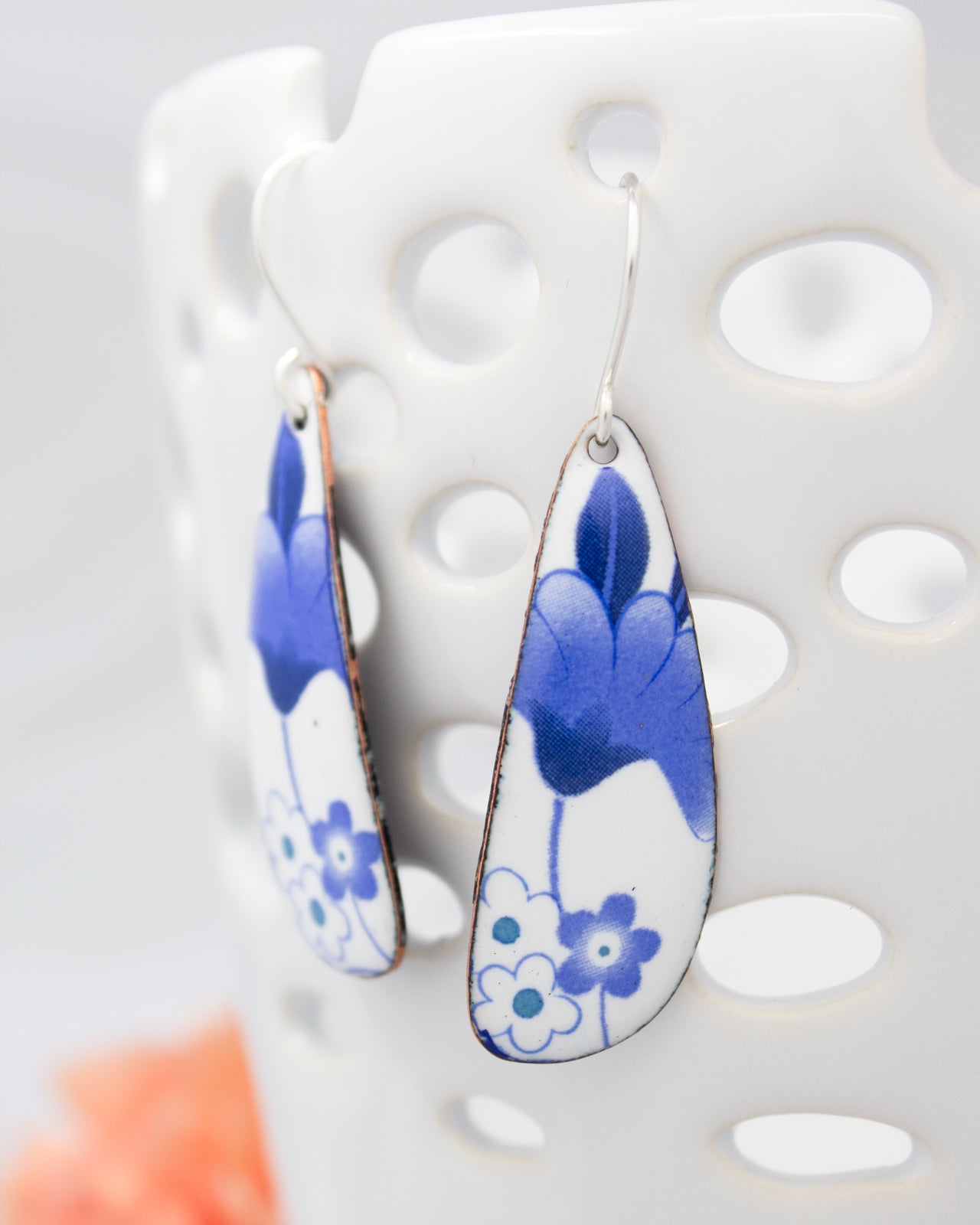 A pair of earrings with blue floral designs on a white background.