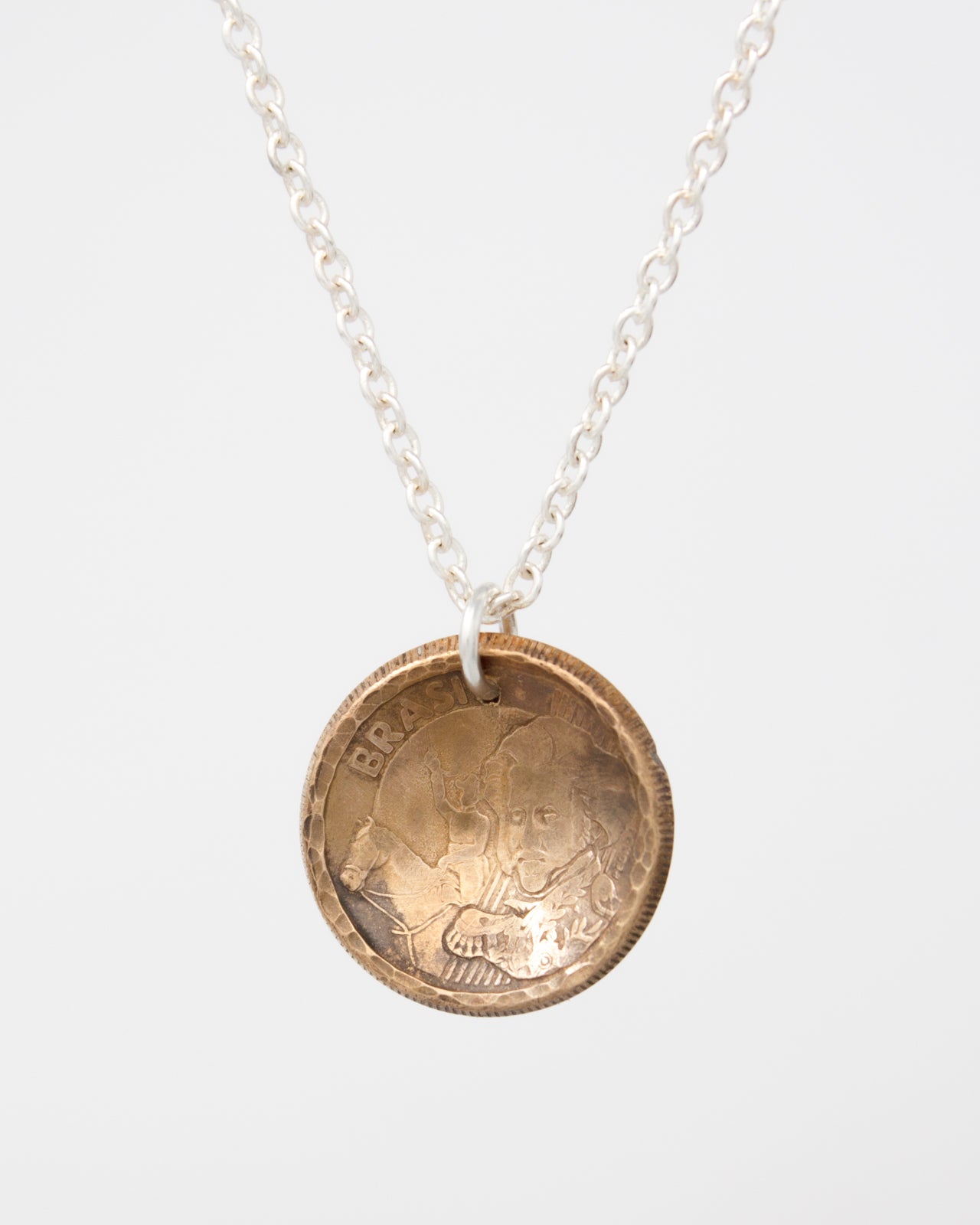 A necklace with a pendant made of a small, circular metal object that appears to be a coin.